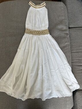 Greek-style halter dress featuring gold trim detail around neckline and waist,